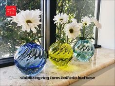 three glass vases with flowers in them on a window sill