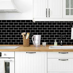 a kitchen with white cabinets and black tile backsplash