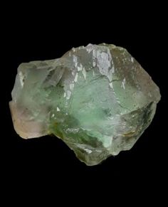 a green rock sitting on top of a black surface