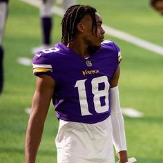 a football player with dreadlocks walking on the field