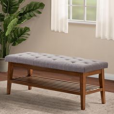 a wooden bench sitting on top of a carpeted floor next to a potted plant