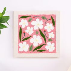 a pink and white flowered painting on a wall next to a potted plant