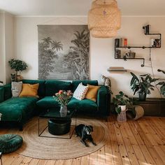 a living room with green couches and potted plants on the floor in front of a painting