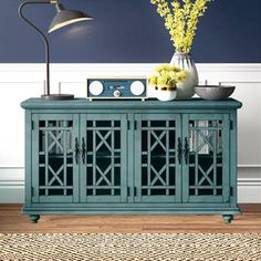 a room with a blue cabinet and yellow flowers on the top shelf next to a lamp