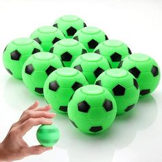 green and black soccer balls being held by a hand