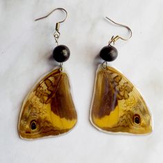 a pair of yellow and brown butterfly wings with black bead dangles on white background