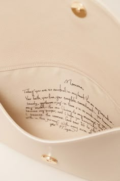 the inside of a white purse with writing on it's side and gold hardware