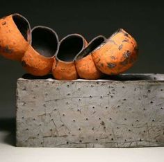 three orange vases sitting on top of a cement block with holes in the middle