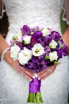 a bride holding a purple and white bouquet