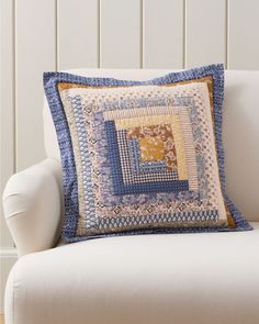 a blue and yellow pillow sitting on top of a white couch next to a wall