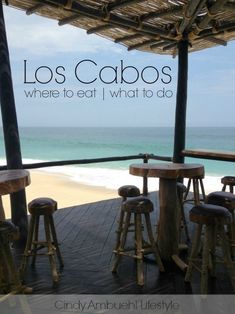 there are four wooden stools at the table by the beach with an ocean in the background