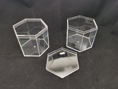 three clear hexagonal boxes sitting on a black surface