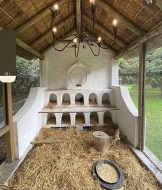 the inside of a chicken coop with hay on the floor and lights hanging from the ceiling