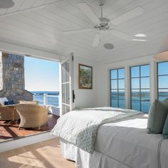 a bedroom with a large bed sitting next to two windows and a stone fireplace in the corner