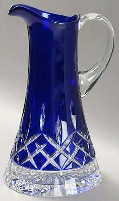 a blue glass pitcher sitting on top of a crystal base with a diamond design in the bottom