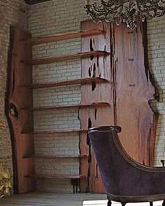 an old fashioned chair sitting in front of a brick wall with a chandelier hanging from the ceiling