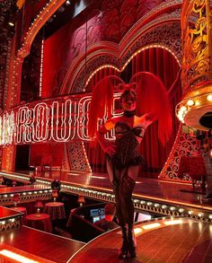 a woman is standing in front of a stage with red lights and decorations on it