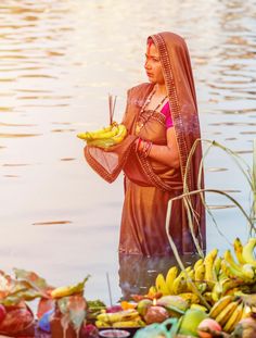 a woman standing next to a bunch of bananas on top of a body of water