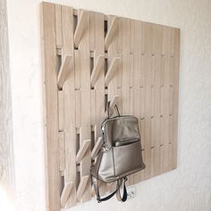 a handbag hanging on a wall next to a wooden sculpture with holes in it