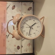 an alarm clock sitting on top of a bed next to a pink and white sheet