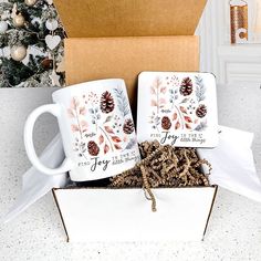 two coffee mugs in a gift box with pine cones