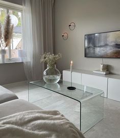 a living room with a glass coffee table and vase filled with flowers on the side