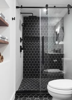 a bathroom with black and white tile on the walls, flooring and shelving