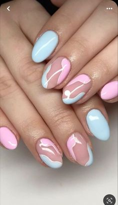 a woman's hands with pink, blue and white nail polishes on them