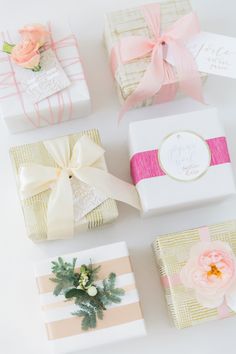 four wrapped gift boxes with ribbons and flowers on them, all decorated in pastel colors