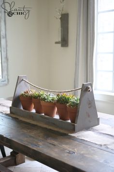 a wooden table topped with potted plants on top of it's sides and a window in the background