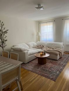 a living room filled with furniture and a rug on top of a hard wood floor