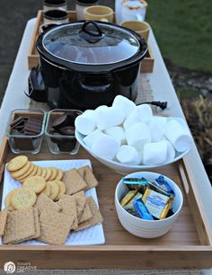 a table topped with lots of food next to a crock pot and an ice bucket