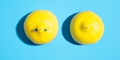 two lemons with faces drawn on them sitting side by side against a blue background