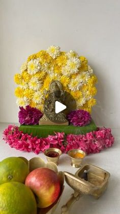 an arrangement of flowers and fruit with a buddha statue in the middle surrounded by other decorations