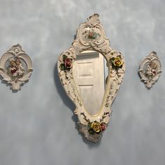 an ornately decorated wall mirror and two mirrors on the side of a wall with flowers