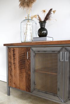 a wooden cabinet sitting next to a vase on top of a table