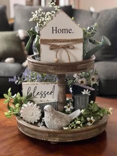 a home sign sitting on top of a wooden tray filled with flowers and greenery