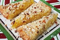 two pieces of pastry on a plate with nuts and powdered sugar toppings, ready to be eaten