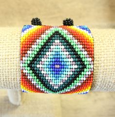 "Colorful and vibrant -- a meticulously designed creation that features a beautiful design and colorful pattern. The bracelet can also act as an anklet.  A ball of beads at the ends works as a clasp for a secure fit. Measurements: Length (including clasp): 7.5\" inches Width: 2\" inches" Hand-strung Multicolor Beaded Bangle, Multicolor Hand-strung Beaded Bangle, Adjustable Multicolor Beaded Bracelet For Festival, Multicolor Bohemian Beaded Bracelets For Festivals, Bohemian Multicolor Beaded Bracelets For Festivals, Adjustable Beaded Bracelets With Colorful Beads For Festivals, Artisan Beaded Bracelets With Colorful Beads For Festivals, Artisan Beaded Bracelet With Colorful Beads For Festivals, Handmade Multicolor Beaded Bangle Bracelets