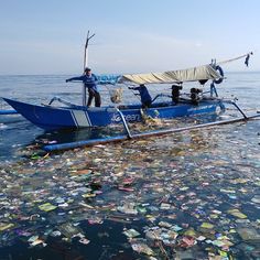 a man on a blue boat in the ocean surrounded by plastic bottles and other trash