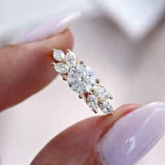 a woman's hand holding an engagement ring with three diamonds on it and the middle finger