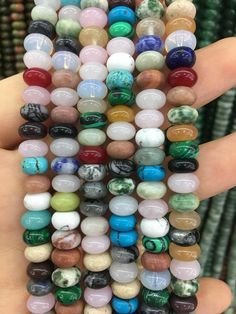 a person holding several different colored beads in their hand, all stacked on top of each other