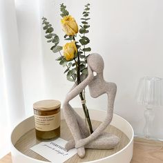 there is a vase with flowers in it and a statue on the table next to it