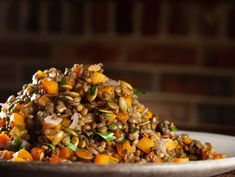 a white plate topped with lentils and carrots on top of a wooden table