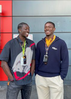 two men standing next to each other in front of a building