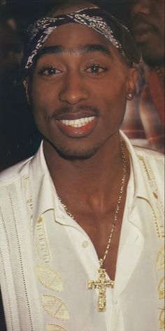 a man in a white shirt with a cross on his chest and a gold chain around his neck