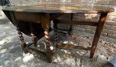 an old wooden table sitting in front of a brick wall