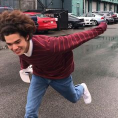 a young man is jumping in the air with his arms spread out and one hand on his hip