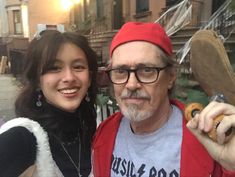 an older man and young woman posing for a photo with doughnuts on the street