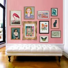 a white bench sitting in front of a pink wall covered with pictures and framed art